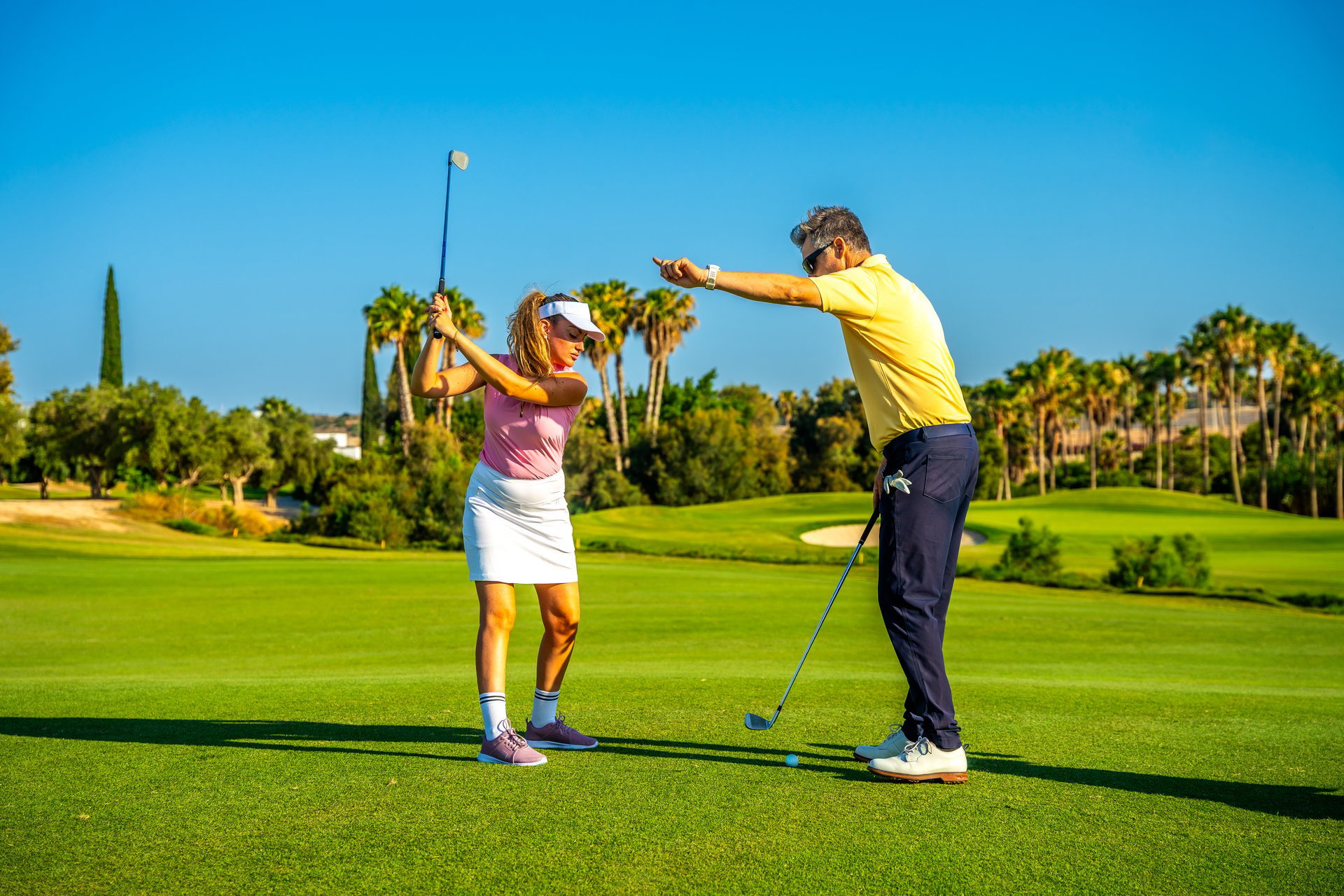 Golf instructor guides a female golfer, providing expert advice